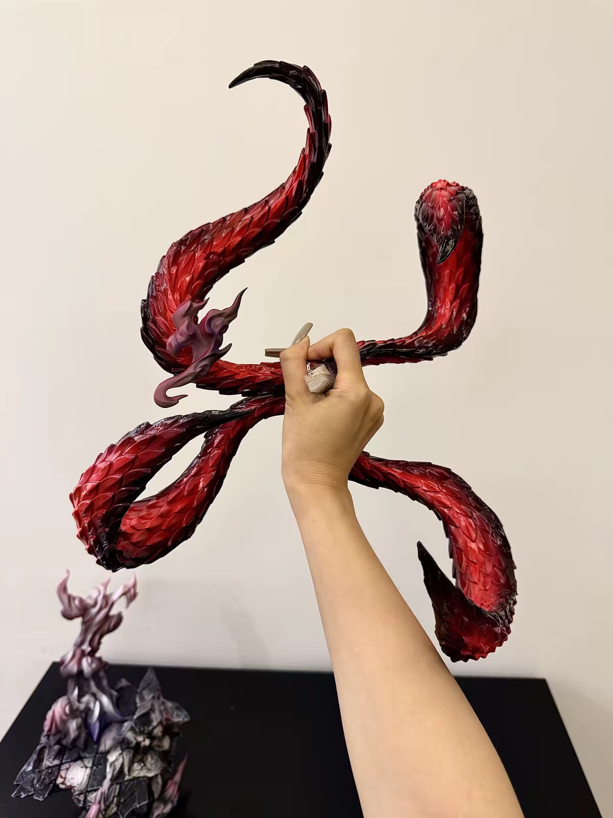 Mano al lavoro sulla finitura del kagune rosso della statua di Kaneki Ken